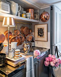 a kitchen with pots and pans hanging on the wall next to a sink filled with dishes