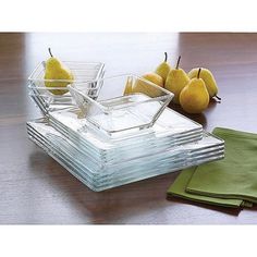 a stack of glass dishes sitting on top of a wooden table next to pears