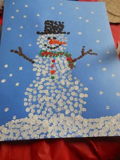 a snowman made out of buttons on a piece of blue paper with white dots