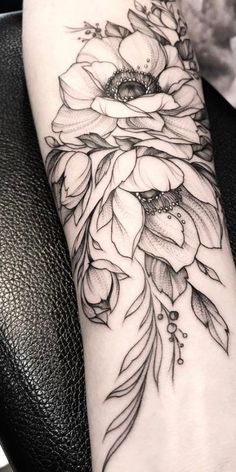 a woman's arm with flowers and feathers tattoo on the left side of her leg