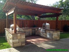 an outdoor kitchen area with grills, sink and bbq in the back yard