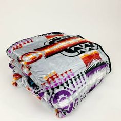 three blankets stacked on top of each other in different colors and patterns, with one blanket folded over the other