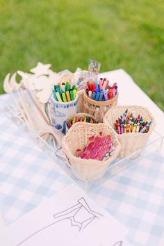 baskets filled with crayons sitting on top of a blue and white checkered table cloth