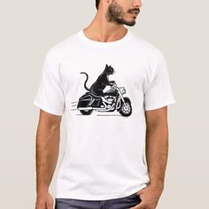 a man wearing a white t - shirt with a black cat riding on the back of a motorcycle