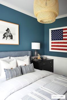 a bedroom with blue walls, white bedding and an american flag on the wall