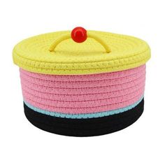 a yellow, pink and black basket with a red button on it's lid