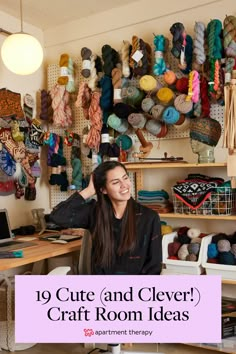 a woman sitting in front of a craft room with lots of yarn on the wall