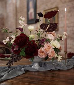 a vase filled with flowers sitting on top of a wooden table next to a candle