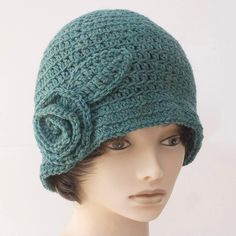 a mannequin head wearing a green crochet hat with a flower on it