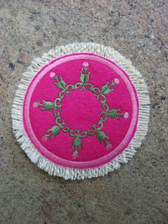 a pink and white rug with green designs on it sitting on a floor next to a wall