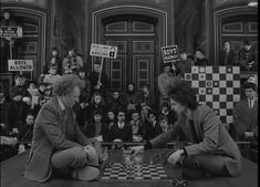 two people playing chess in front of a crowd