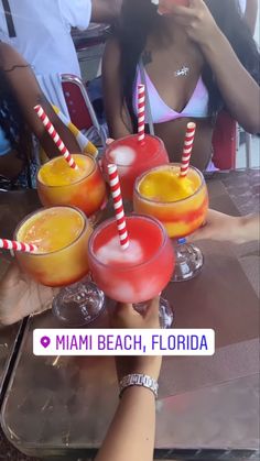 people are holding up drinks at a beach bar with red and yellow striped straws