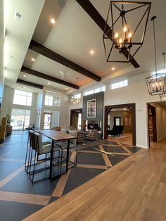 a large open living room with wood floors and chandelier hanging from the ceiling