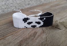 a beaded bracelet with black and white squares on it sitting on top of a wooden table