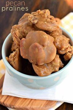 a blue bowl filled with peanut butter pecan pralies on top of a wooden table