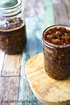 two jars filled with food sitting on top of a wooden table