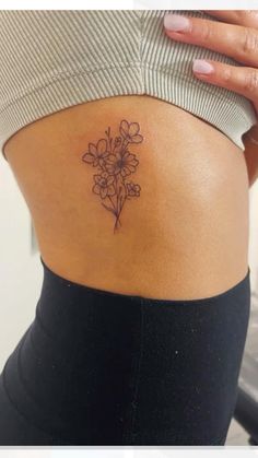 a woman with a flower tattoo on her lower back side ribcage, showing it's thinness