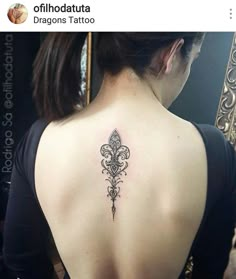 the back of a woman's neck with a fleur de lis tattoo on it