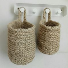 two crocheted baskets are hanging on the wall next to a coat hook and hooks