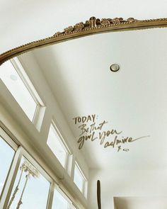 a mirror that has writing on it in the middle of a room with large windows