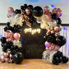 an arch made out of balloons with the words happy birthday written in gold and black