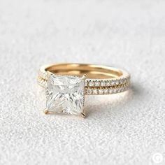 a princess cut diamond ring set with pave diamonds on the band and side stones