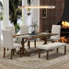 a dining room table with white chairs and a bench in front of an open fire place