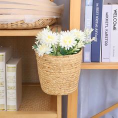 a basket filled with flowers sitting on top of a book shelf next to some books