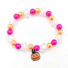 an orange and pink beaded bracelet with a small pumpkin charm on it's side