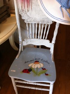 a white chair with ladybugs painted on it and a hat sitting on top of it