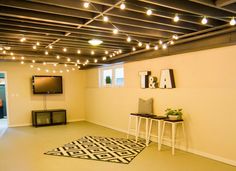 an empty room with lights strung from the ceiling, and a rug on the floor