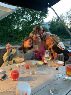 four women sitting at a table with wine glasses in front of them and one woman taking a selfie