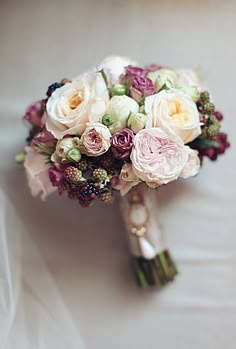 a bridal bouquet with pink, white and green flowers sits on the back of a chair