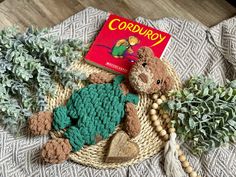 a teddy bear sitting on top of a table next to a book and some plants