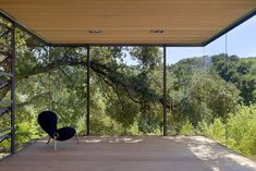 an empty chair sitting on top of a wooden floor next to a tree filled forest