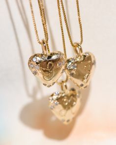 two heart shaped pendants hanging from gold chains