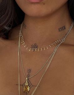 a woman with tattoos on her chest wearing gold chains and a cross tattoo design necklace