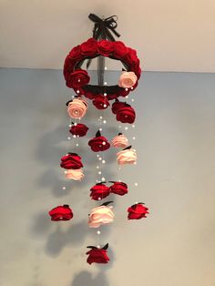 a wind chime with roses and pearls hanging from it's side on a wall