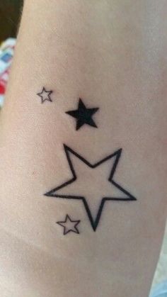 a small star tattoo on the side of a woman's leg, with three smaller stars above it