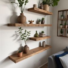 three wooden shelves with plants and vases on them in the corner of a living room