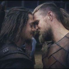 two men with long hair and beards standing next to each other