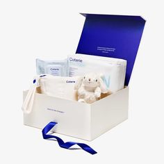 a white box with blue ribbon and stuffed animal in it