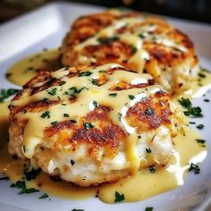 two crab cakes covered in cheese on a white plate