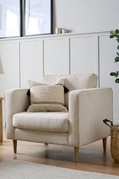 a living room with a chair, table and two pictures on the wall behind it