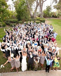 a large group of people posing for a photo in front of some trees and bushes