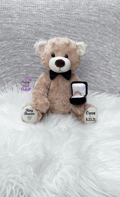 a brown teddy bear sitting on top of a white fur covered bed next to a tag