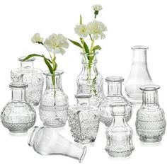 a group of vases with flowers in them sitting next to each other on a white surface