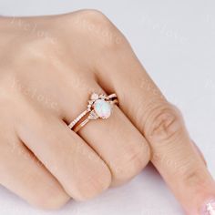 a woman's hand wearing a ring with an opal stone in the center