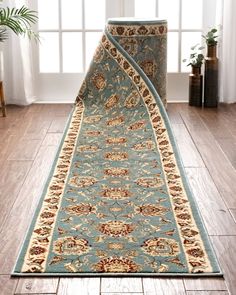 a large blue rug with an intricate design on the floor in front of a window