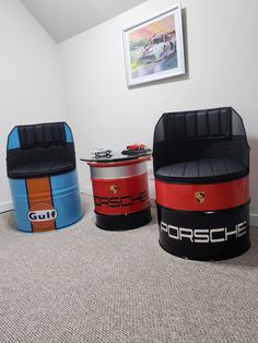 three colorful storage containers sitting on top of carpeted floor next to a wall with pictures above them